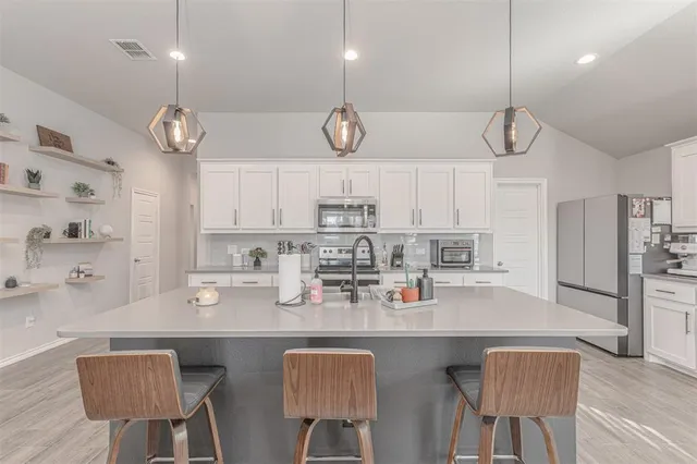 a kitchen with stainless steel appliances a table chairs and a stove