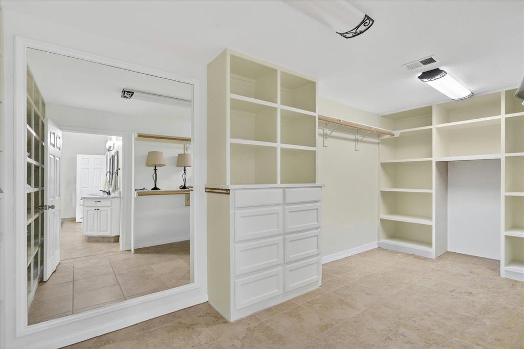 8877 Random Road Fort Worth, TX 76179 - Photo 17 of 40 Walk-in closet featuring extensive built-in shelving, integrated drawers, and a full-length mirror