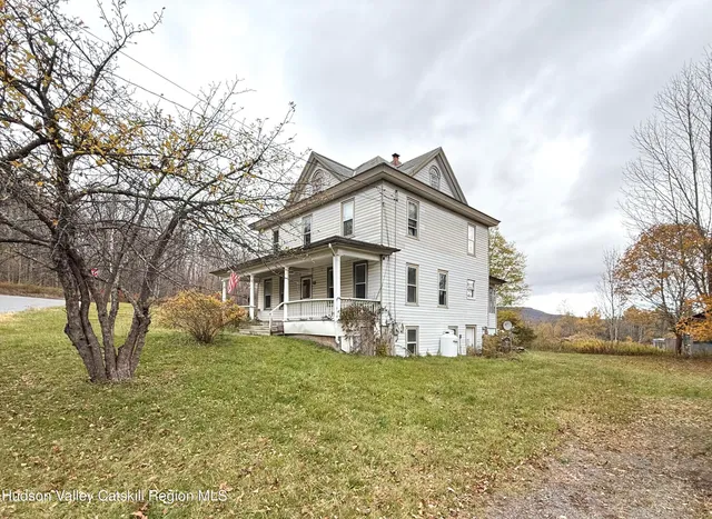 a white house with a big yard and large trees