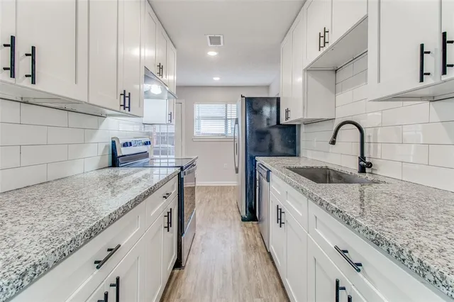 a kitchen with stainless steel appliances granite countertop a sink a stove top oven a counter space and cabinets