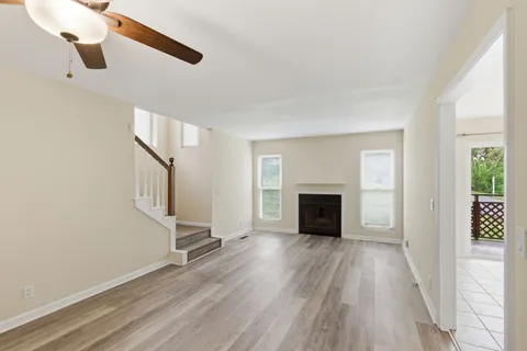 a view of a livingroom with wooden floor a fireplace and windows