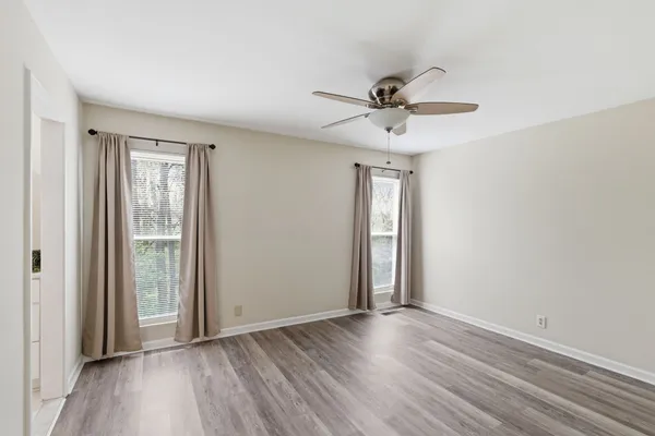 a view of an empty room with wooden floor and a window