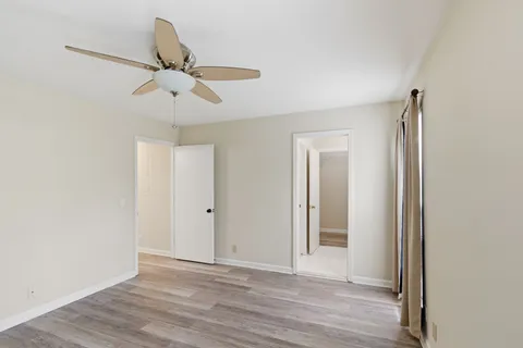 a view of a room with wooden floor and ceiling fan