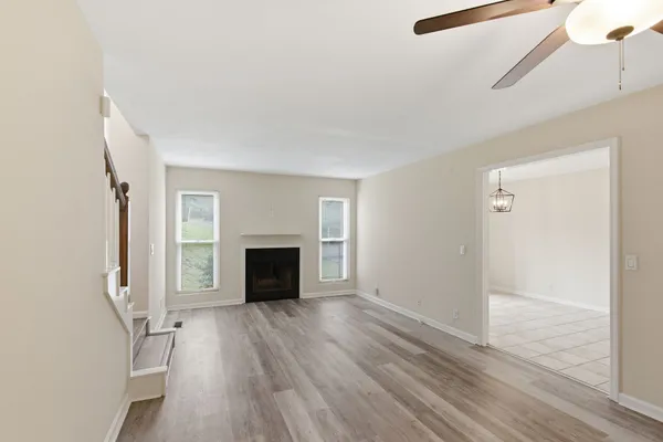 an empty room with wooden floor fireplace and windows