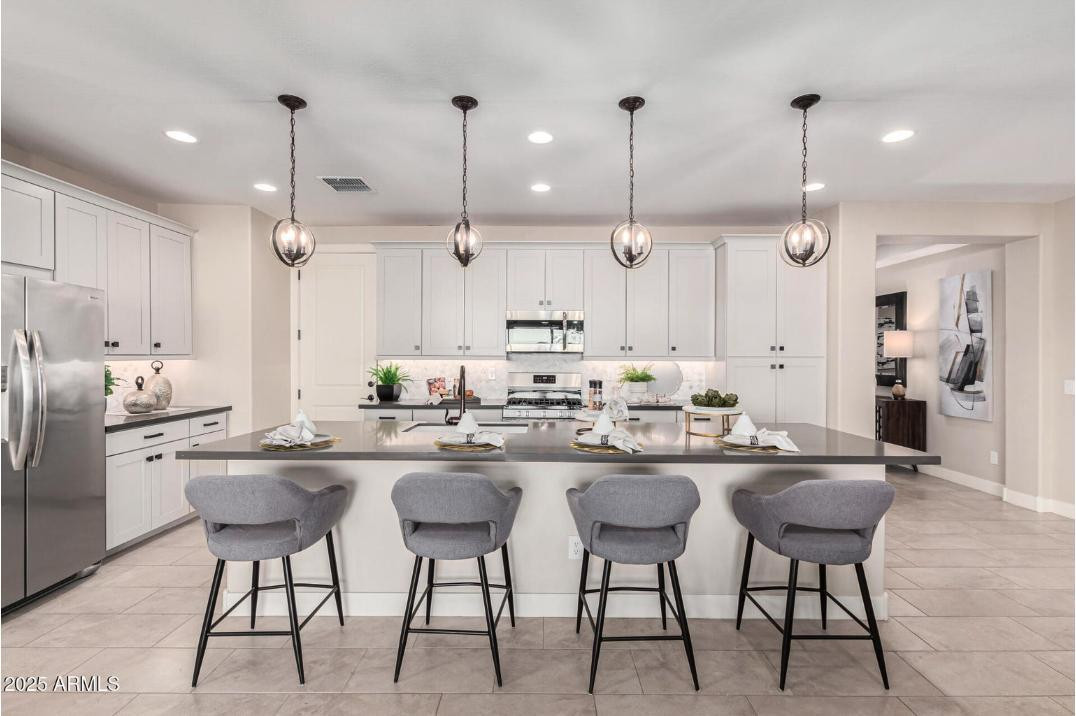 17386 West Bloomfield Road Surprise, AZ 85388 - Photo 12 of 31 a kitchen with stainless steel appliances kitchen island granite countertop a dining table chairs and white cabinets