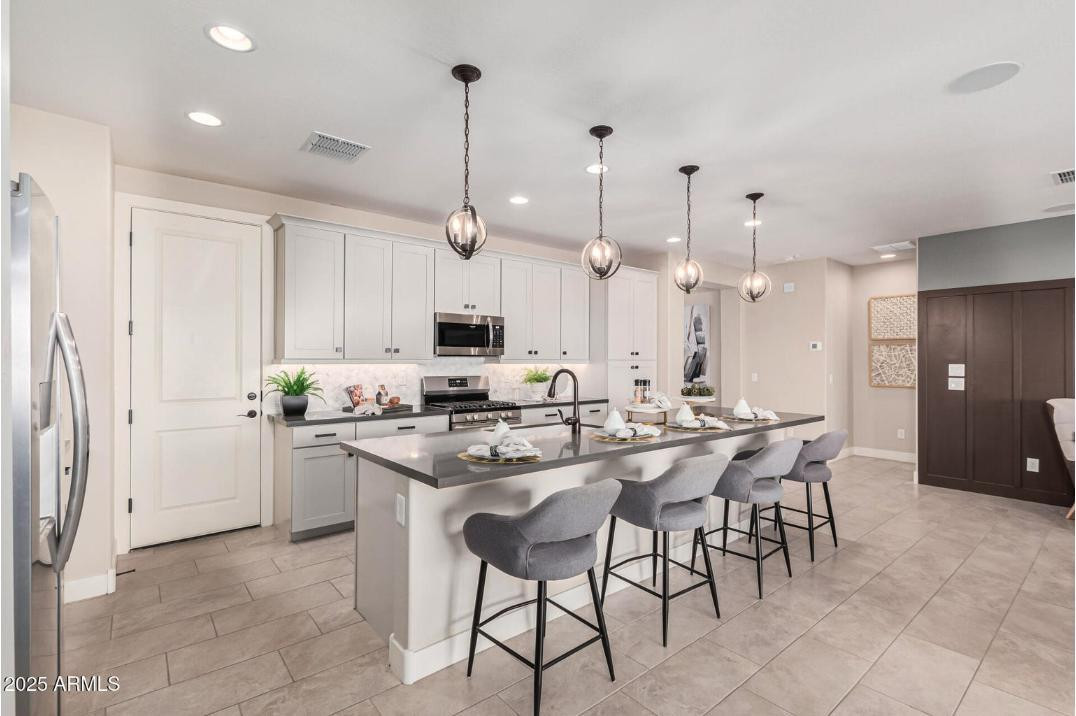 17386 West Bloomfield Road Surprise, AZ 85388 - Photo 13 of 31 a kitchen with stainless steel appliances kitchen island a table chairs sink and cabinets