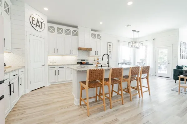 a kitchen with stainless steel appliances kitchen island granite countertop a table chairs and a refrigerator