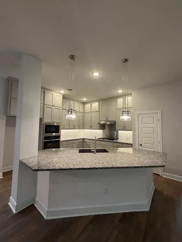 a large kitchen with granite countertop a sink a counter top space and cabinets