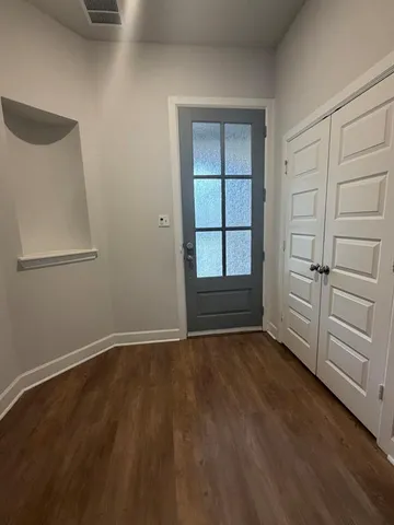 an empty room with wooden floor closet and windows