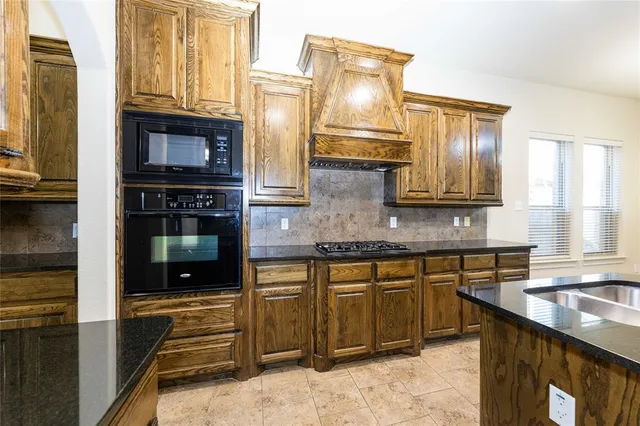 a kitchen with stainless steel appliances granite countertop a refrigerator a stove and a sink with wooden floor