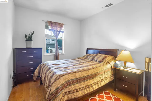 a bedroom with a bed and a lamp on dresser