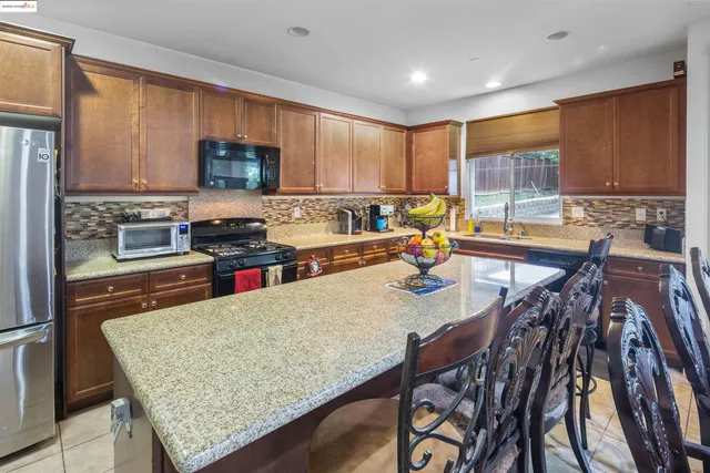 a kitchen with stainless steel appliances granite countertop a stove top oven a sink a dining table and chairs