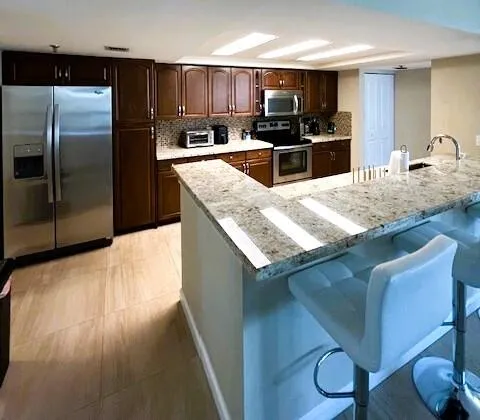 a kitchen with kitchen island granite countertop a sink refrigerator and microwave