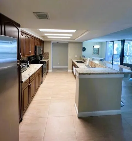 a kitchen with kitchen island granite countertop a sink and a stove top oven