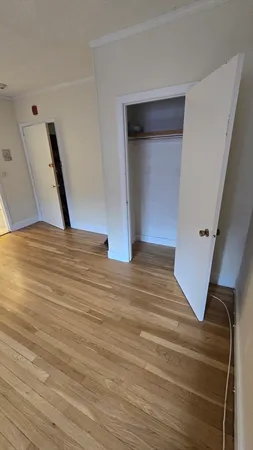 a view of an empty room with wooden floor and stairs