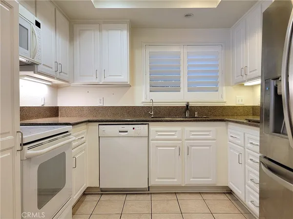 a kitchen with white cabinets granite counter tops and a stove