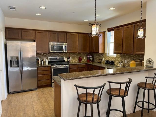 a kitchen with stainless steel appliances granite countertop a stove a sink a microwave a refrigerator and white cabinets