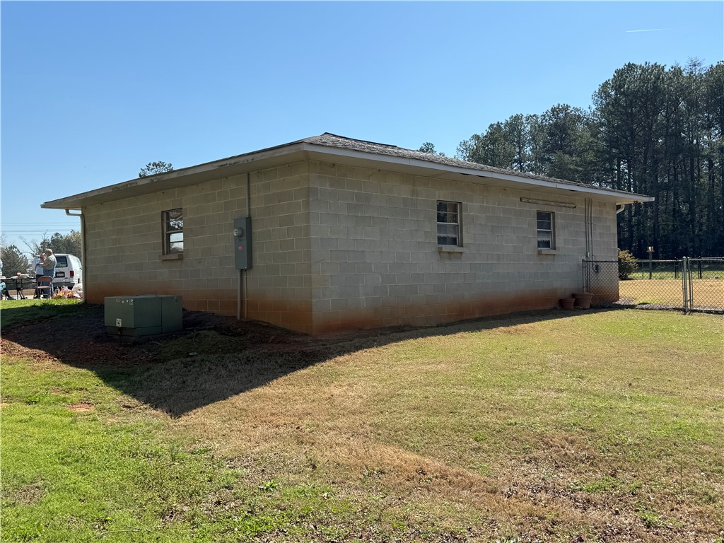 121 Nautical Way Anderson, SC 29625 - Photo 7 of 37 A modest block structure offers a secure perimeter with chain link fencing, nestled in a natural setting.
