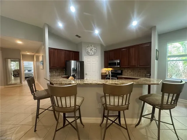 a kitchen with a dining table chairs and refrigerator
