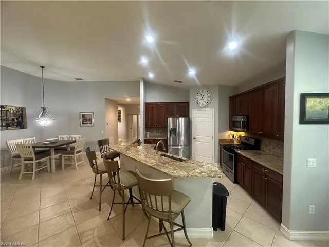 a kitchen with stainless steel appliances kitchen island granite countertop a sink a stove a dining table and chairs