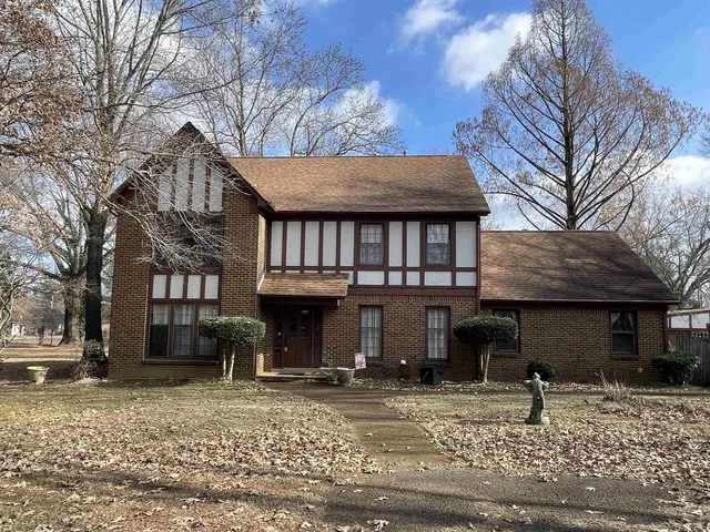 a view of a house with a yard and large tree