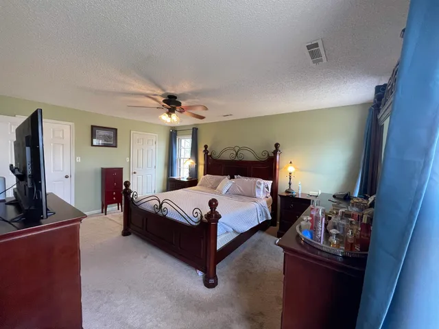 a bedroom with bed and a flat tv screen on dresser
