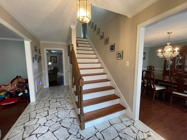 a view of a hallway to a livingroom with wooden floor and stairs
