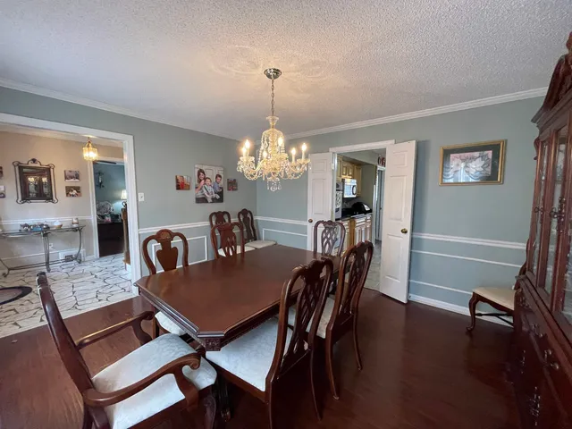 a dining room with furniture a chandelier and wooden floor