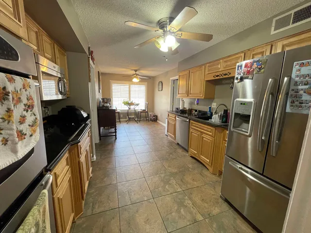 a kitchen with stainless steel appliances granite countertop a refrigerator a sink a stove and white cabinets