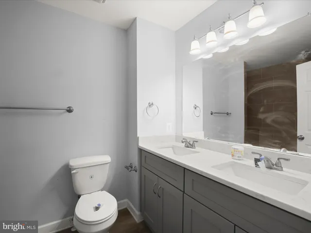 a bathroom with a toilet a sink a light fixture and a mirror
