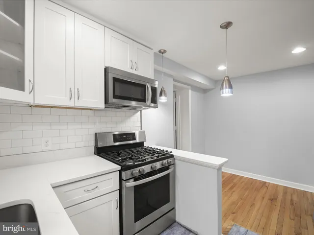 a kitchen with stainless steel appliances granite countertop white cabinets a sink a stove and a refrigerator