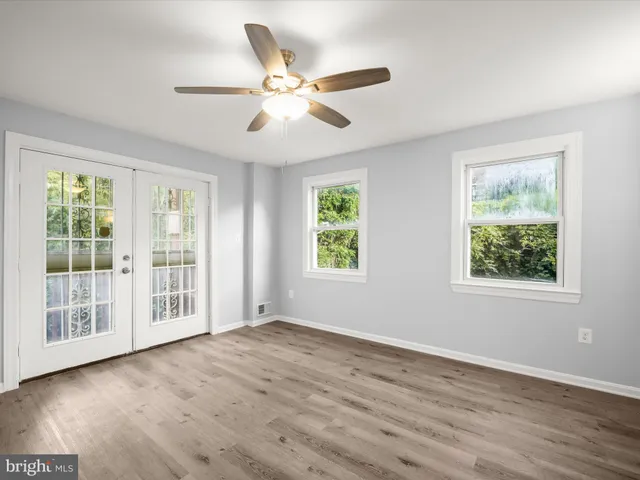 a view of an empty room with wooden floor and a window