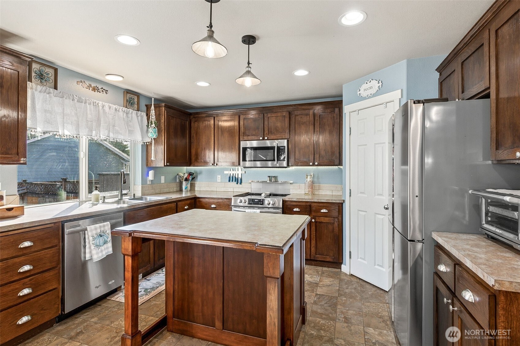 7074 Inlay Street Southeast Lacey, WA 98513 - Photo 5 of 28 a kitchen with a refrigerator a sink and wooden cabinets