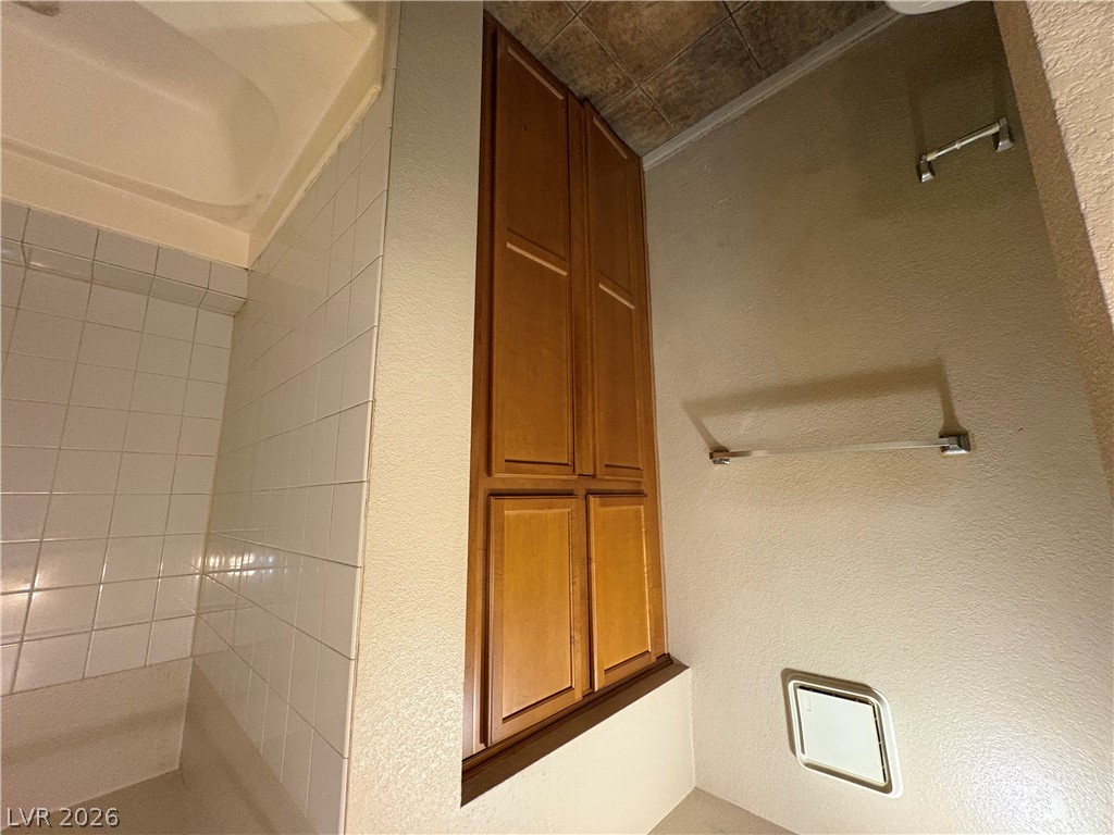 9325 West Desert Inn Road, Unit 123 Las Vegas, NV 89117 - Photo 25 of 36 Integrated storage cabinetry complements the tiled shower area, maximizing utility in this practical bathroom.
