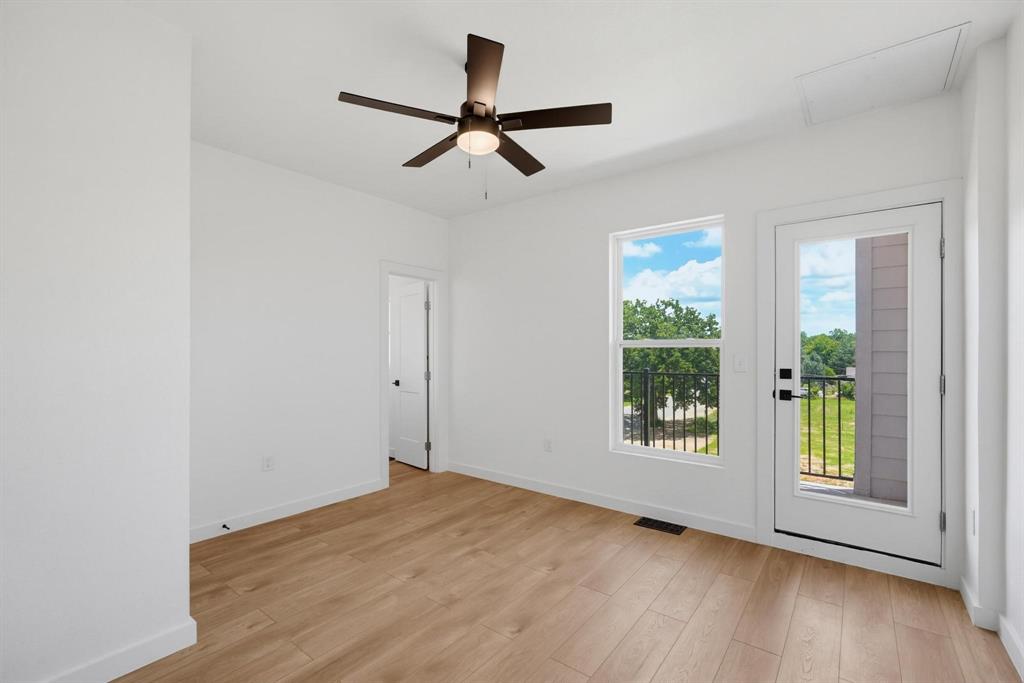 504 South O Connor Road Irving, TX 75060 - Photo 18 of 23 Spacious room featuring wood-finish flooring, a contemporary ceiling fan, ample natural light from the window, and direct exterior access through a glass-paneled door