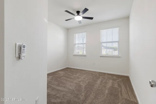 an empty room with ceiling fan and window