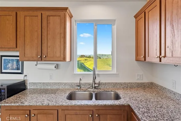 a kitchen with granite countertop a sink a window and stainless steel appliances