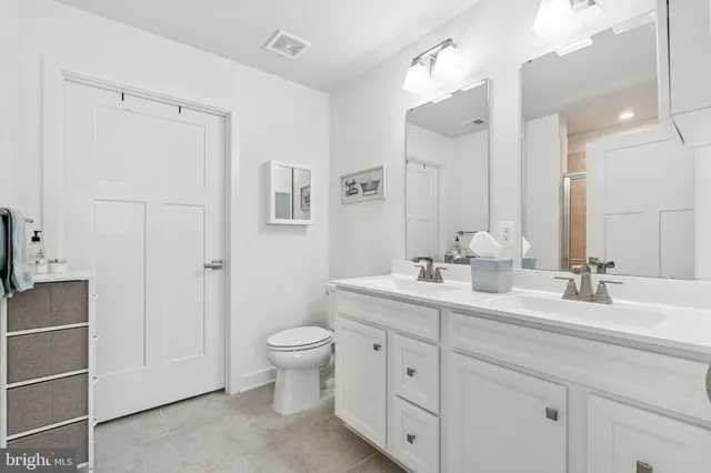 a bathroom with a double vanity sink mirror and toilet