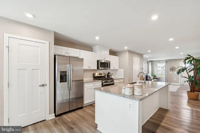 a large kitchen with kitchen island a large counter top stainless steel appliances and cabinets