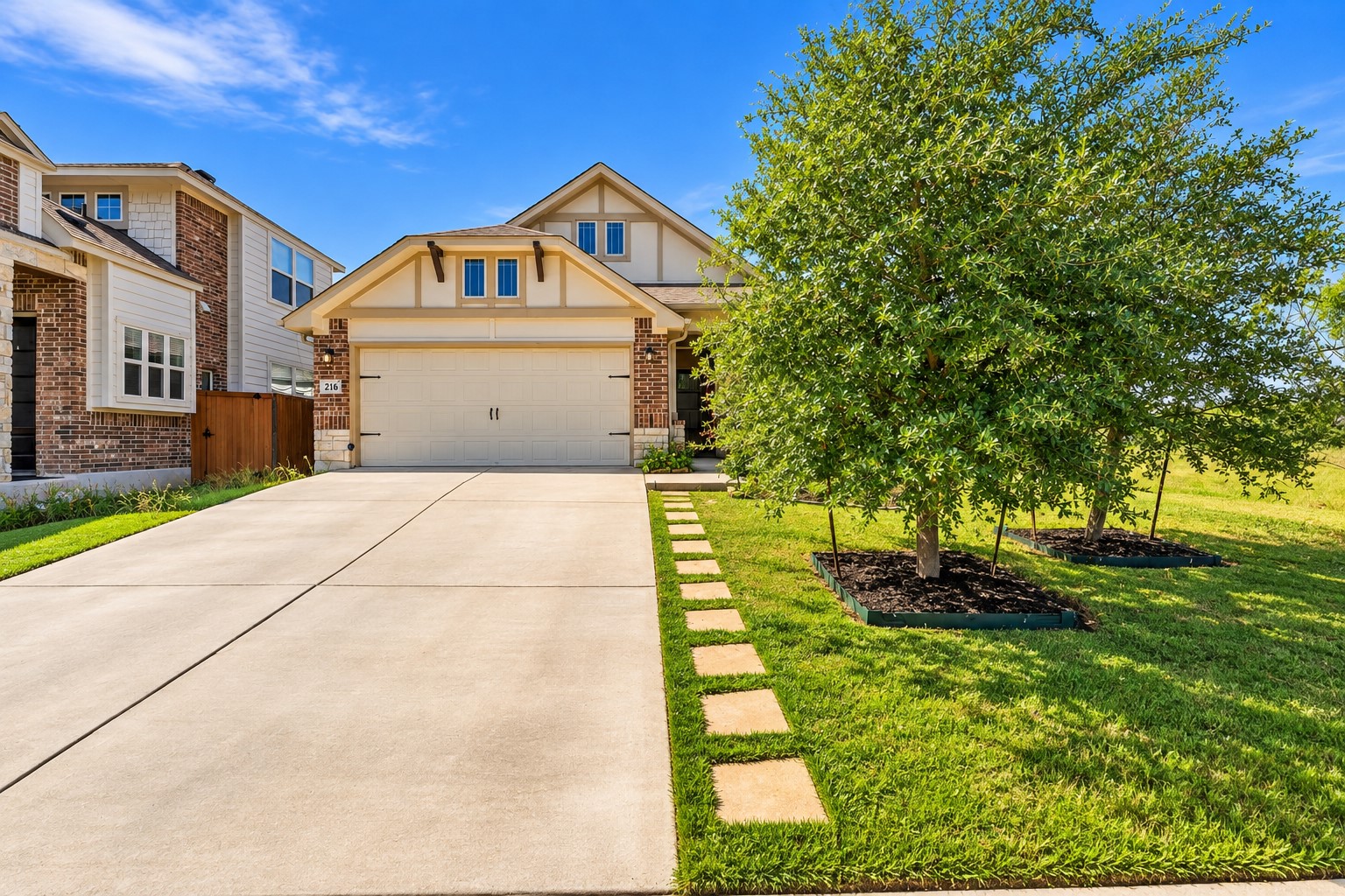216 Spinnaker Loop Kyle, TX 78640 - Photo 2 of 23 Manicured green lawn and stepping stones frame the wide concrete driveway leading to the garage.