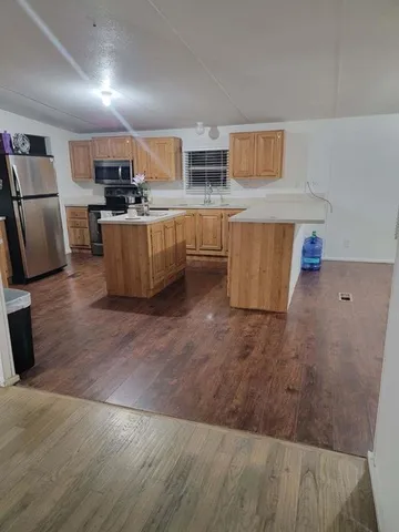 a kitchen with kitchen island a stove a sink dishwasher a refrigerator and cabinets with wooden floor