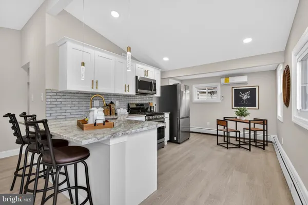 a kitchen with stainless steel appliances granite countertop a stove a sink dishwasher a stove a refrigerator a microwave oven with white cabinets and wooden floor