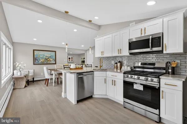 a kitchen with stainless steel appliances kitchen island granite countertop a stove top oven a sink dishwasher a dining table and chairs with wooden floor
