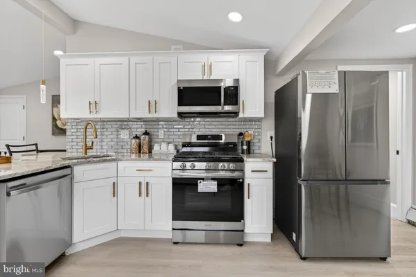 a kitchen with stainless steel appliances granite countertop a refrigerator stove a sink and a microwave