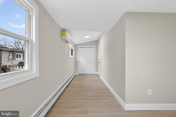 a view of a hallway with wooden floor and a bathroom