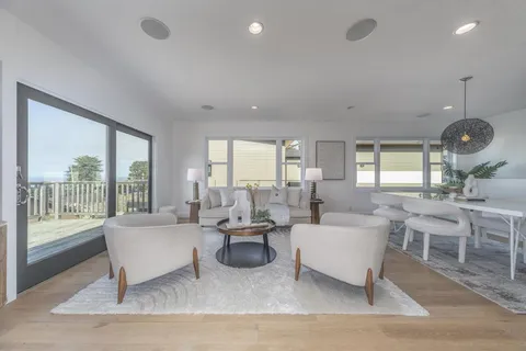 a living room with furniture large window and wooden floor