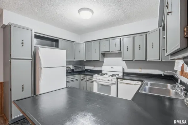 a kitchen with granite countertop a refrigerator stove top oven and sink