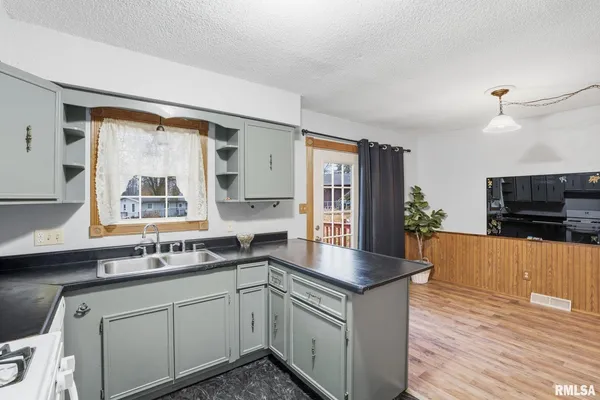 a kitchen with stainless steel appliances granite countertop a sink a stove and a wooden floors