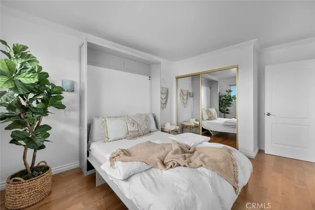 a bed sitting in a bedroom next to a window and a potted plant