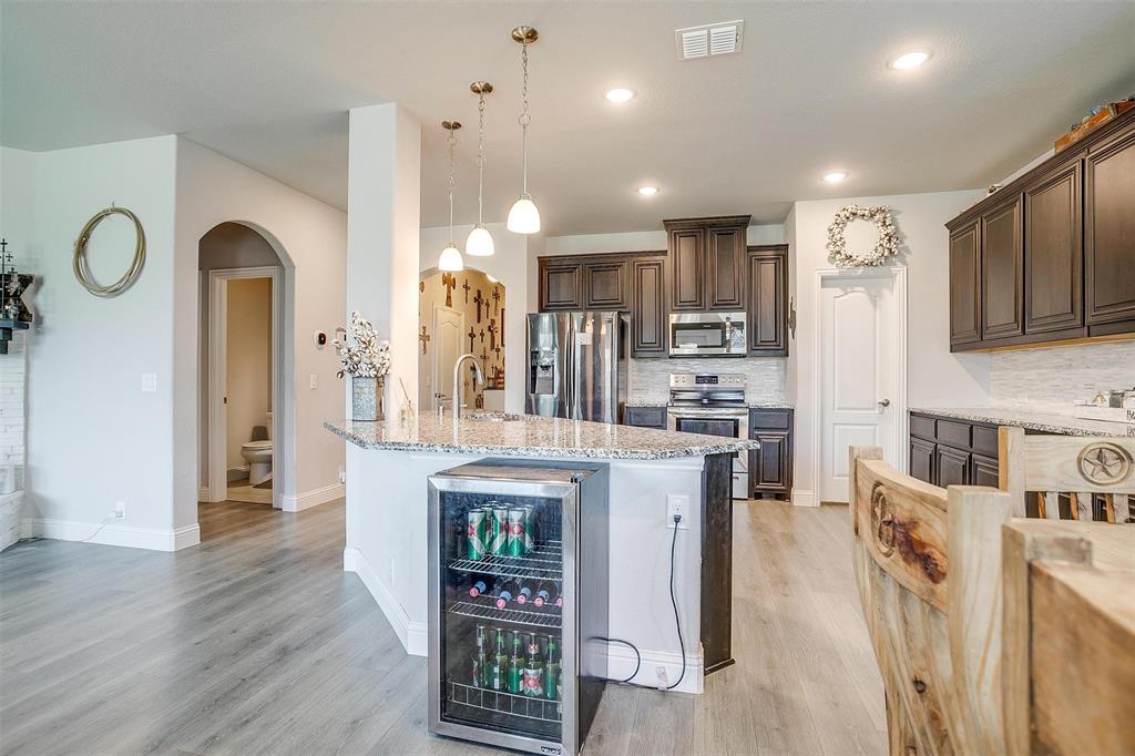 433 Joseph Lane Crowley, TX 76036 - Photo 11 of 40 a open kitchen with stainless steel appliances granite countertop a refrigerator a oven a stove and a dining table with wooden floor